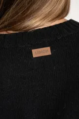 Sweater de punto negro, corte oversize, con cuello redondo y apliques de tachas plateadas en los hombros.