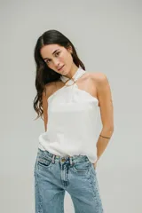 Blusa de crepe twill color blanco, con escote halter y detalle de hebilla metálica dorada en el cuello.