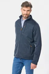 Campera de felpa gris melange, con interior de polar, cuello alto, cierre frontal completo y bolsillos laterales. Presenta detalles de apliques en cuero sintético en el pecho y la manga.