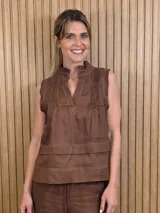 Musculosa marrón sin mangas, con cuello alto, escote en V y detalles de pespuntes blancos en contraste. Presenta pliegues y alforzas frontales.