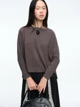 Buzo tejido de punto en color marrón, con cuello a la base, mangas largas y silueta cómoda. Presenta tajos laterales en el ruedo que aportan movimiento.