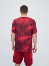 Remera de entrenamiento Umbro del Club Nacional de Football, modelo Press, para hombre. Diseño en tonos de rojo con patrón estampado tipo humo o abstracto, cuello redondo y mangas cortas. Incluye el logo de Umbro y el escudo del club en el pecho.
