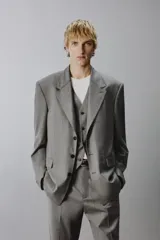 Blazer de corte regular confeccionada en tejido con lana, color gris. Presenta cuello con solapas de muesca, manga larga, bolsillos de vivo en el pecho y bolsillos de solapa en la cadera. Cuenta con cierre frontal de botones y aberturas en la espalda.
