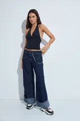 Top halter negro de silueta ajustada y diseño cropped, con escote profundo en V y frunce bajo el busto. Presenta espalda descubierta con lazo regulable en el cuello.