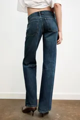 Jeans de mezclilla azul oscuro con efecto lavado, tiro bajo y pierna ancha extra larga. Modelo de cinco bolsillos con cierre frontal de cremallera y botón metálico.