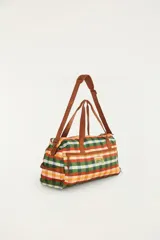 Bolso de viaje tipo duffel multicolor con estampado de cuadros vichy en tonos verde, rojo, amarillo y celeste. Cuenta con asas de mano y correa de hombro ajustable marrón, con detalles de la marca y bolsillos con cierre.