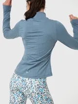 Campera deportiva de entrenamiento con cierre frontal completo, cuello alto y mangas largas con orificio para pulgar. Confeccionada en tejido técnico suave de color azul denim melange, cuenta con bolsillos laterales con cierre y costuras reforzadas.