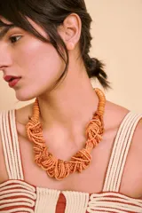 Collar corto de cuentas de madera en tonos salmón y tostado, con diseño entrelazado de múltiples hilos.