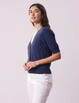 Cárdigan blanco tejido con escote en V, abertura frontal con botones y mangas cortas abullonadas con puño.