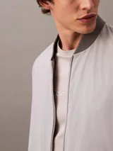 Remera gris claro de algodón con cuello redondo y manga corta. Presenta un estampado tonal con el logo de Calvin Klein Jeans en el pecho.