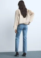 Jeans flare de tiro medio color celeste, confeccionados en tejido denim de algodón con elasticidad. Presentan cierre delantero con cremallera y botón, trabillas para cinturón y dos bolsillos de parche en la parte delantera.