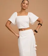 Pollera midi recta color blanco, de laise con bordados geométricos y lazo en la cintura.