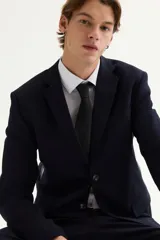 Blazer de hombre color azul marino oscuro, de corte slim fit, con solapas de muesca finas, botonadura sencilla de un botón visible, bolsillo superior insertado y dos bolsillos delanteros con solapa.