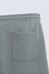 Bermuda de algodón color beige claro, corte relajado (relaxed fit), con cintura elástica ajustable mediante cordón y bolsillos laterales y trasero de plastrón.