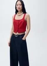 Chaleco de corte sastre con cuello escotado y tirantes anchos. Presenta cierre frontal con botones ocultos bajo tapeta y dos bolsillos de ribete delanteros. Confeccionado en una mezcla de viscosa, lino y algodón con forro interior de algodón.