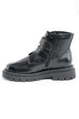 Bota corta de cuero negro con suela track dentada y dos correas decorativas con hebillas metálicas en el lateral. Presenta un diseño de puntera cuadrada y cierre lateral.