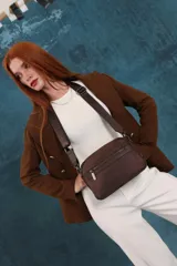 Bandolera de diseño moderno y funcional, confeccionada en nylon color marrón claro. Cuenta con múltiples compartimentos con cierre metálico, herrajes plateados y una correa ancha ajustable con detalle de marca.