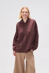 Canguro marrón con capucha, cordones ajustables, bolsillo tipo canguro y corte holgado.