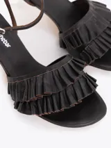 Sandalia de cuero vacuno con volados en la capellada, tira ajustable al tobillo y original taco esférico transparente.