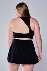 Conjunto deportivo compuesto por un top tipo bra de escote redondo y una pollera tableada corta, ambos en color negro con el logo 'bk.' estampado en blanco en la banda elástica.