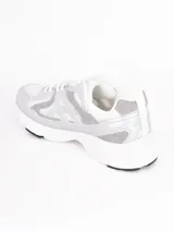 Zapatillas deportivas de estilo urbano, color blanco con detalles en plateado, confeccionadas en malla y material sintético, con suela de goma.