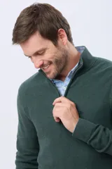 Buzo de tejido texturizado color verde oscuro, con cuello alto, cierre frontal parcial y manga larga.