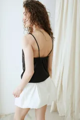 Top negro de jersey con tirantes finos y escote redondo, decorado con apliques circulares de nácar distribuidos por toda la prenda.