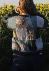 Saco de punto con diseño patchwork en tonos azules, decorado con flores bordadas. Presenta cuello redondo con lazo de ajuste y etiqueta de cuero sintético en la espalda.