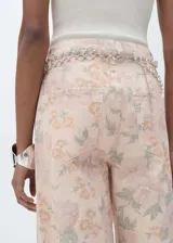 Pantalón jeans de corte wide leg y tiro alto, confeccionado en algodón con estampado floral en tonos suaves. Presenta diseño de cinco bolsillos, cierre frontal con cremallera y botón, y trabillas en la cintura.