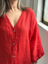 Camisa oversize de lino color rojo, con escote en V, mangas largas amplias y cierre frontal con botones.