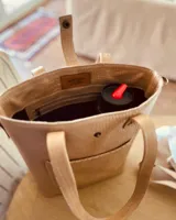 Bolso matero color beige con textura croco, con correa larga regulable y bolsillo exterior para lentes.