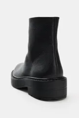 Botín plano de piel con suela track de volumen, punta redonda y cierre lateral mediante cremallera.