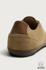 Zapatilla deportiva barefoot de hombre, confeccionada en piel con acabado serraje de color marrón, puntera redondeada, suela fina de goma oscura y detalles en cuero liso en el talón.
