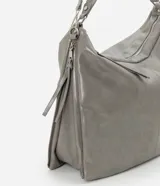 Bolso grande tipo hobo desestructurado, color gris claro con acabado ligeramente brillante o envejecido. Cuenta con dos asas cortas y una correa larga desmontable. Presenta detalles de cierres o tiradores decorativos en los laterales y cierre principal superior con cremallera.