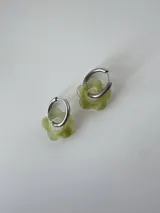 Aros de acero quirúrgico con argolla mediana y dije colgante en forma de flor de acrílico verde translúcido.