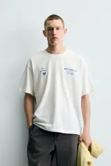 Camiseta de corte relajado con cuello redondo y manga corta. Presenta un diseño con estampados en tono azul con efecto lavado en la parte frontal.
