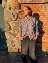Camisa de corte oversize con estampado de rayas verticales en color negro y blanco, cuello camisero y mangas largas con puños anchos.