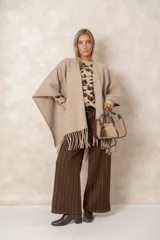 Ruana abierta de color beige, confeccionada en tejido de punto con terminación de flecos en el ruedo.