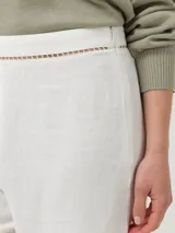 Pantalon de corte recto y tiro alto, confeccionado en una mezcla de lino orgánico y viscosa. Presenta detalles de calado decorativo en la cintura y en el ruedo de las piernas.