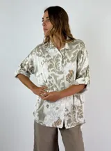 Camisa manga 3/4 con estampado abstracto en tonos beige y blanco, con cuello clásico y cierre con botones.