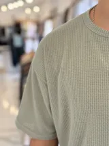 Remera oversize de tejido de punto color beige, de manga corta y cuello redondo.