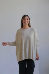 Sweater de punto con hilo lurex color beige, de corte holgado, cuello redondo y mangas largas con puños ajustados. Presenta un diseño con líneas verticales en relieve y aberturas laterales en el ruedo.