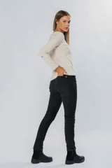 Pantalón de pana elastizada color negro, corte ajustado, cinco bolsillos y accesorios metálicos personalizados.