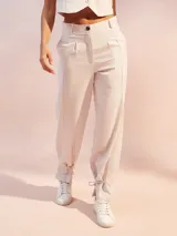 Pantalón de corte sastrero en color beige, confeccionado en mezcla de lino. Presenta pinzas frontales, cierre con botón y detalle de lazo ajustable en los tobillos.