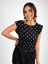 Blusa sin mangas de viscosa color negro con estampado de lunares blancos, cuello redondo y cintura fruncida con elástico.