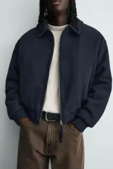 Cazadora de paño acolchada en su interior para hombre, de corte cropped y color azul marino. Cuenta con cuello solapa, mangas largas, bolsillos de doble vivo en la cadera, detalles de acabado en rib elástico en puños y cintura, y cierre frontal de cremallera metálica con doble carro.
