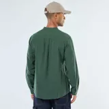 Camisa de manga larga de franela verde oscuro, con cuello mao y cierre frontal de botones marrones. Posee un bolsillo de parche en el pecho izquierdo.