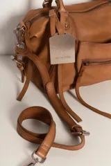 Cartera de cuero color negro con efecto lavado y desgastado, estilo vintage. Cuenta con múltiples bolsillos con cierre delantero, tiras colgantes y doble asa corta de mano.