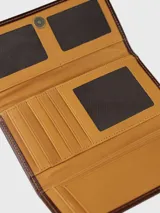 Billetera combinada de cuero en tonos marrón y camel, con solapa frontal de pelo vacuno estampado y detalle de placa con el logo de la marca.