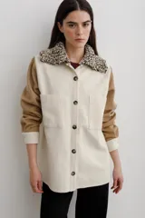 Camisa de paño de lana con diseño bicolor, cuerpo en color crema y mangas en color tostado. Presenta un cuello tejido con textura, cierre frontal con botones y dos bolsillos frontales tipo parche.